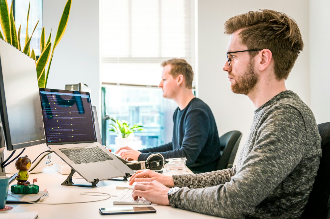 A developer working at a desk with a laptop showing code